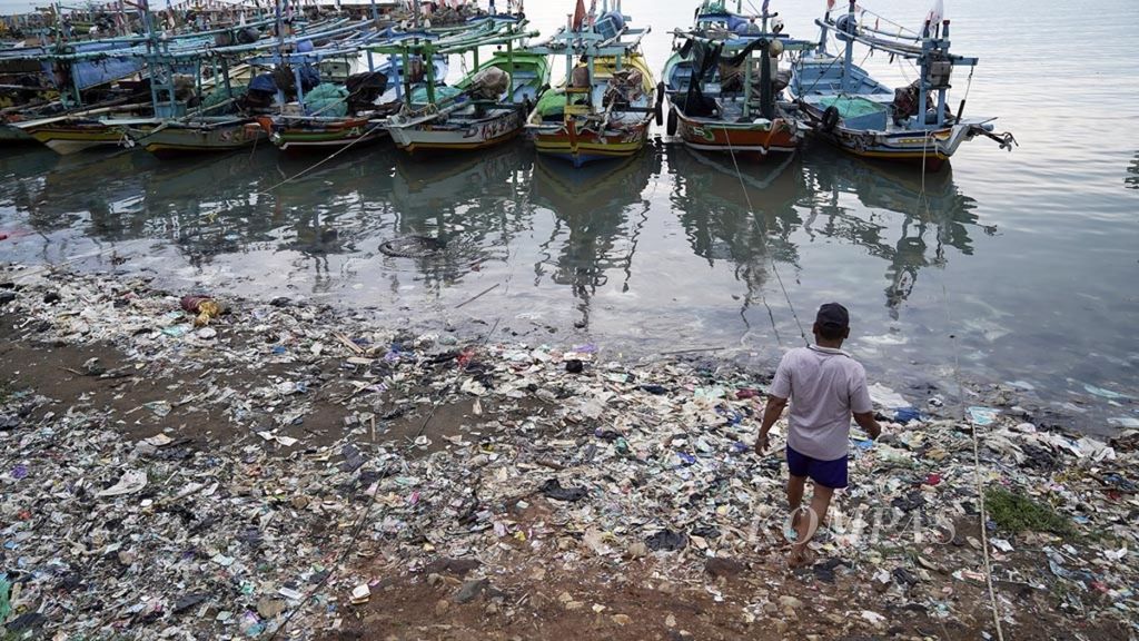 Warga melintasi timbunan sampah yang didominasi sampah plastik di pesisir Desa Dadap, Kecamatan Juntinuyat, Kabupaten Indramayu, Jawa Barat, awal Desember 2018. 