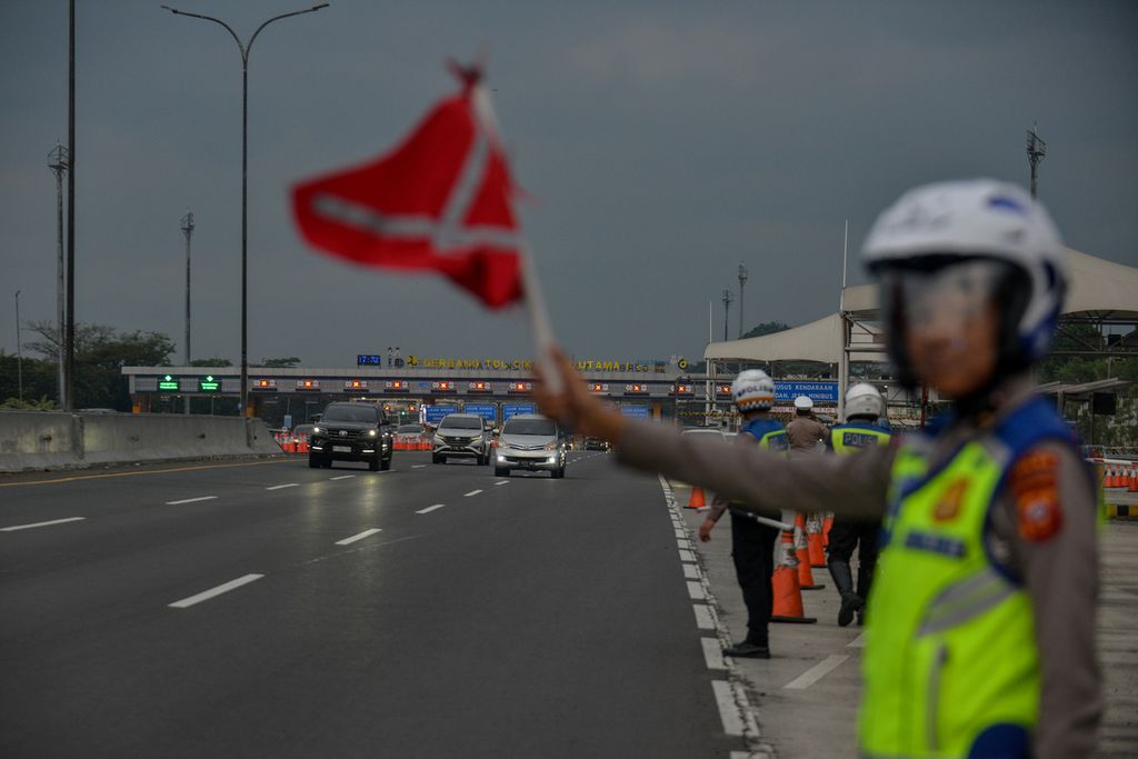 Polisi mengatur lalu lintas di Gerbang Tol Cikampek Utama, Karawang, Jawa Barat, Senin (24/4/2023). Rekayasa lalu lintas satu arah atau<i> one way </i>dan <i>contraflow </i>mulai diberlakukan kepolisian untuk mengurangi kemacetan saat arus balik Lebaran 2023. 
