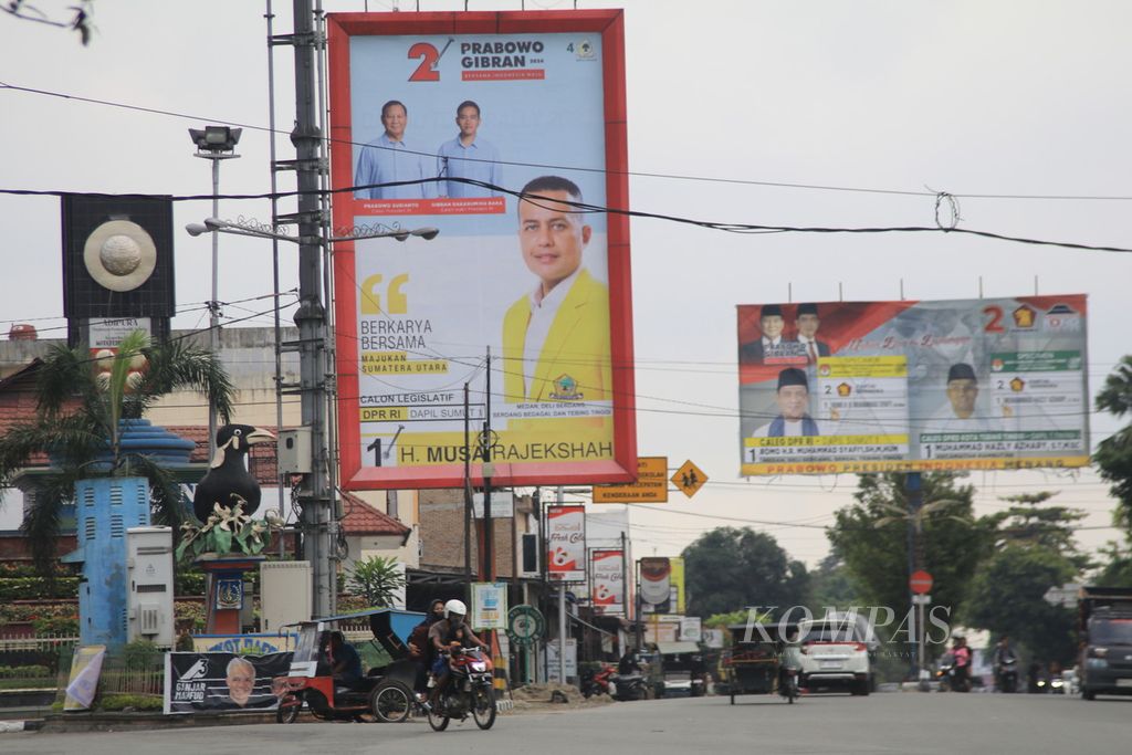 Masyarakat melintas di bawah baliho besar calon anggota Dewan Perwakian Rakyat yang terpampang di Daerah Pemilihan Sumatera Utara I di Kota Tebing Tinggi, Sabtu (20/1/2024).