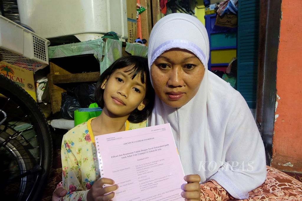 Annisa Tri Octaviani Andini (kiri) bersama ibunya, Juwariyah, di rumah mereka di Kelurahan Tugu Utara, Kecamatan Koja, Jakarta Utara, Sabtu (30/10/2016), menunjukkan dokumen keikutsertaan Annisa dalam uji klinik vaksin dengue yang digagas Sanofi Pasteur.