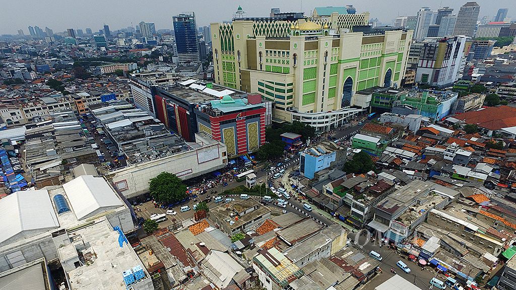 Pasar Tanah Abang Blok A (atas) bersanding dengan toko-toko kecil di   jantung perdagangan di Tanah Abang, Jakarta Pusat, Minggu (12/11). Kawasan ini juga menjadi simpul pertemuan antarmoda transportasi dan pusat pedagang kaki lima yang belum tertata dengan baik. 