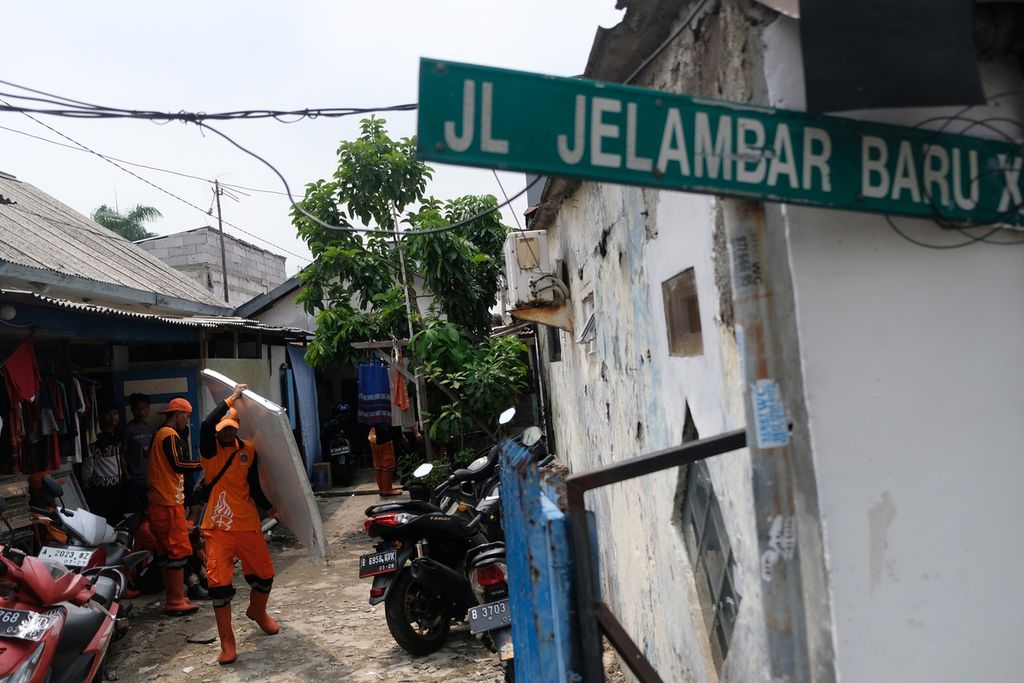 Petugas Penanganan Prasarana dan Sarana Umum (PPSU) membawa sisa puing-puing bangunan yang terbang akibat hujan disertai angin kencang di Jalan Jelambar Baru X, Kecamatan Grogol Petamburan, Jakarta Barat, Minggu (27/11/2022).