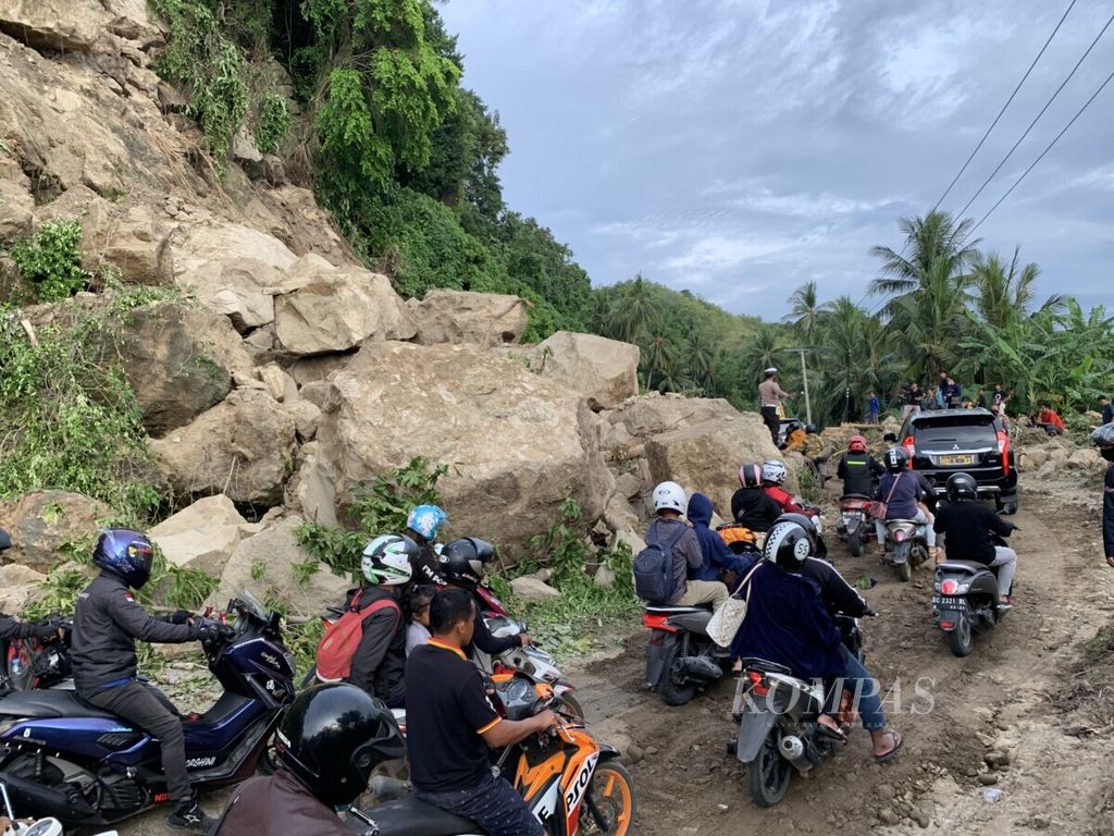 Kendaraan melintas di antara reruntuhan batu yang jatuh dari tebing di sisi jalan di Desa Onang Kecamatan Tubo Sendana, Majene, Sulawesi Barat, Senin (18/1/2021). Bebatuan di tebing dan perbukitan di sepanjang jalur antara kota Majene dan perbatasan Mamuju rawan longsor terlebih pascagempa dengan magnitudo 6,2 pada Jumat (15/1/2021).