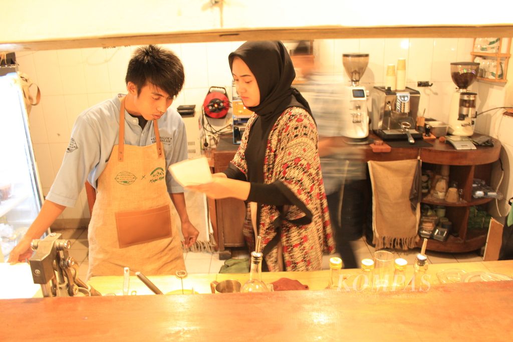 Arifin (baju biru) melihat pesanan kopi di Kedai Kue Balok Mang Salam X Kopi Kang! di Kota Bandung, Jawa Barat, Selasa (8/11/2022). Arifin adalah penyandang disabilitas rungu yang bekerja di kedai itu. 