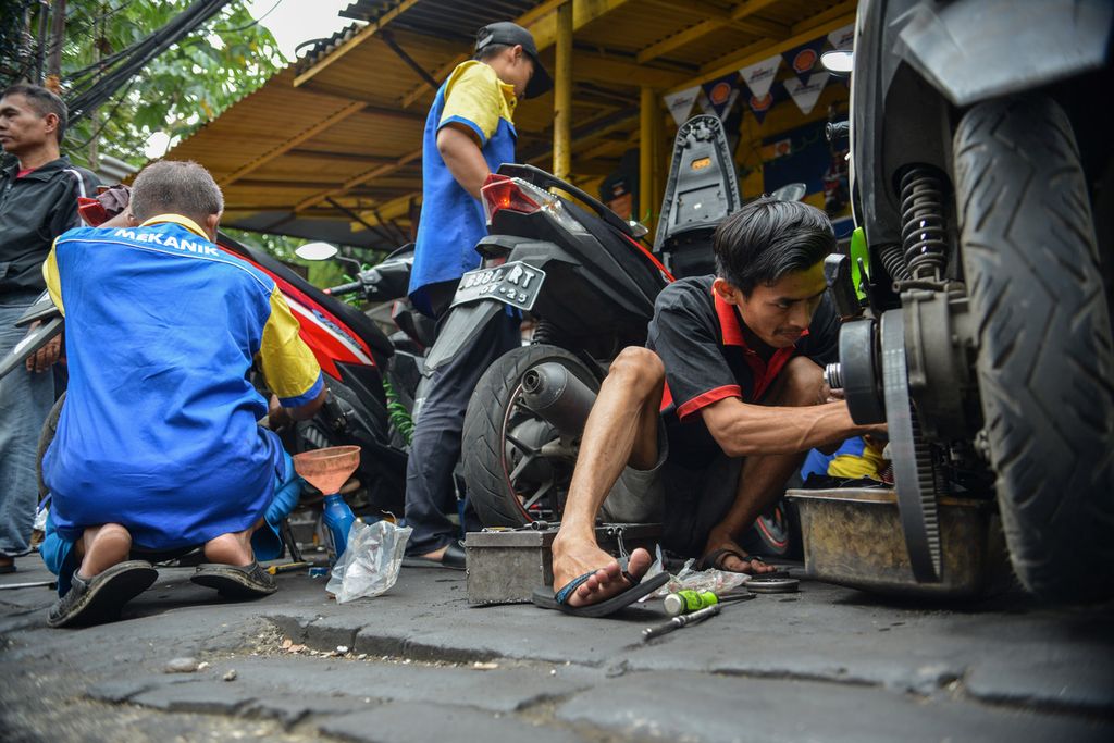 Mekanik memperbaiki sepeda motor milik warga di salah satu bengkel sepeda motor di kawasan Jalan Palmerah Utara, Jakarta Pusat, Minggu (16/4/2023). 