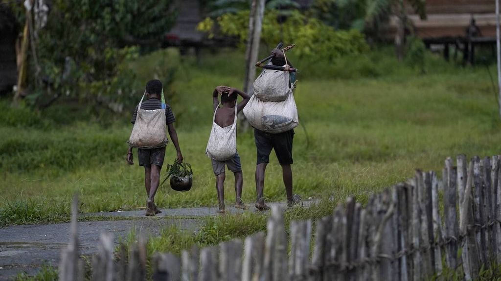 Warga melewati jalan beton di Kampung Sinimburu, Distrik Yaniruma, Kabupaten Boven Digoel, Papua, Minggu (8/3/2020). Sebanyak 79 KK tinggal di kampung yang berada di tepi Sungai Deiram ini. Warga masih berpola hidup berburu dan meramu. KOMPAS/AGUS SUSANTO