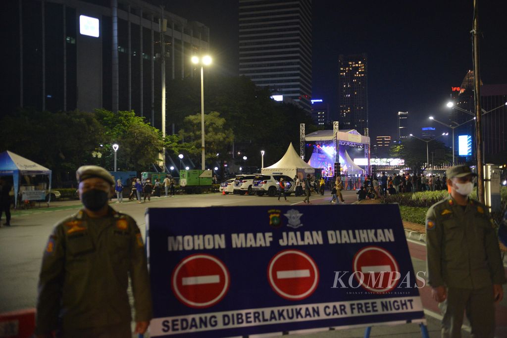 Petugas Satuan Polisi Pamong Praja berjaga di depan Jalan Sudirman, Jakarta Pusat, setelah ditutup jelang perayaan Tahun Baru 2023, Sabtu (31/12/2022). 