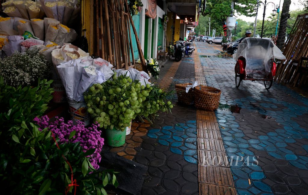 The rickshaw driver crosses the area of flower sellers who are busy taking orders for the Kaesang-Erina wedding party on Jalan Slamet Riyadi, Surakarta City, Central Java, Friday (9/12/2022). The wedding party of President Joko Widodo's son had a broad impact on the economy of the surrounding residents from various kinds of craft to service business lines.