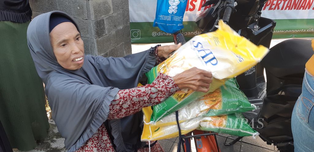 Nasuha (60), warga Sidoarjo, memborong beras SPHP di acara pasar murah Dinas Pertanian dan Ketahanan Pangan Sidoarjo, Jumat (8/3/2024). 