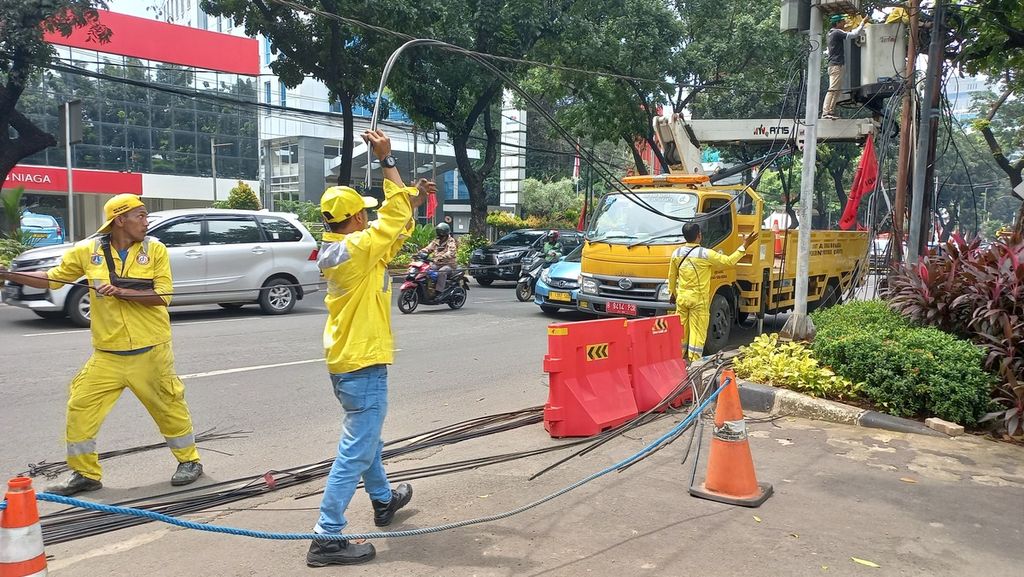 Petugas Dinas Bina Marga DKI Jakarta, Rabu (11/1/2023), melakukan pemotongan kabel udara dan menurunkan kabel-kabel yang sudah terpotong di Jalan Kebon Sirih, Jakarta Pusat.