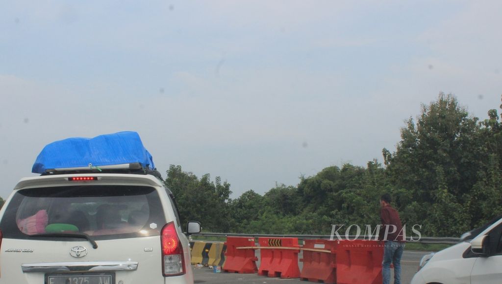 Seorang pengendara turun dari mobilnya untuk menggeser pembatas jalan portabel yang dipasang di tempat berputar kendaraan di Jalan Tol Cikopo-Palimanan, Jumat (29/4/2022) siang. 