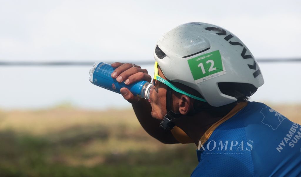 Pebalap minum di sela-sela mengikuti etape kedua Cycling de Jabar 2023 di Cikalong, Tasikmalaya, Jawa Barat, Minggu (9/7/2023).