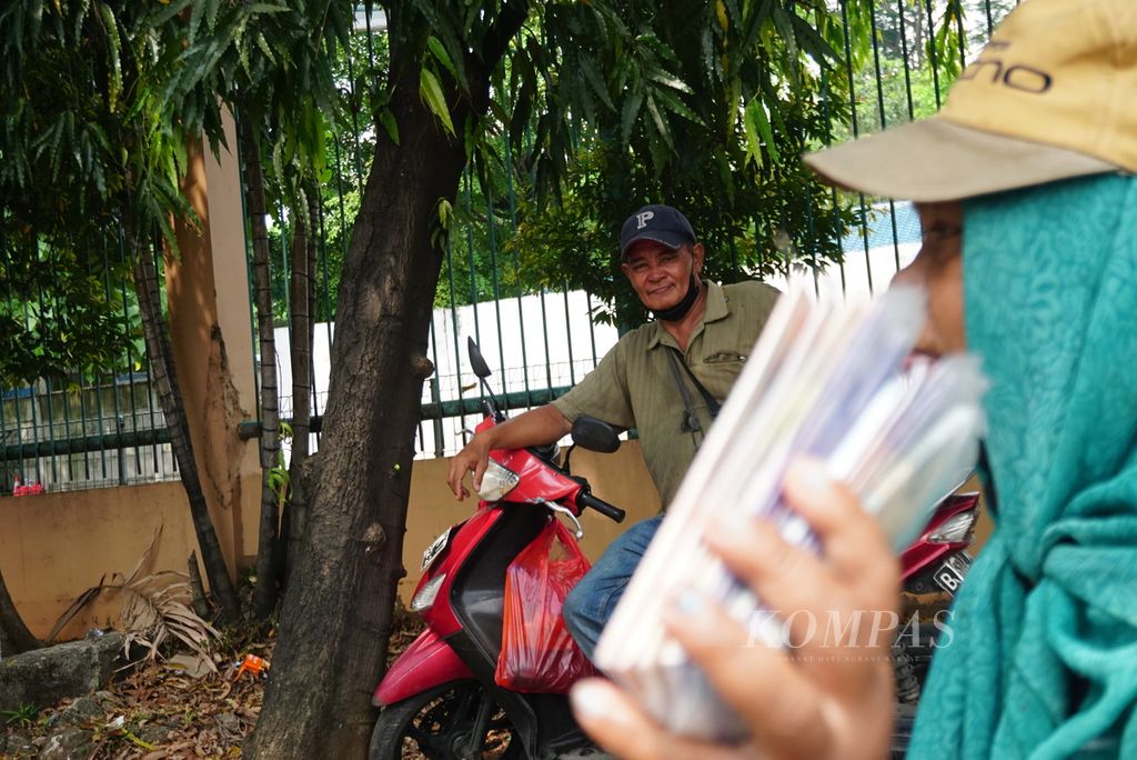 Anggiat Tampubolon beristirahat sementara istrinya, Alam Siahaan, menjajakan kantong-kantong plastik berisi pecahan uang kertas Rp 2.000, Rp 5.000, dan Rp 10.000 di tepi jalan di daerah Pondok Indah, Jakarta Selatan, Selasa (18/4/2023). Hampir semua penjaja jasa penukaran uang tersebut adalah perantau Batak dari Sumatera Utara.