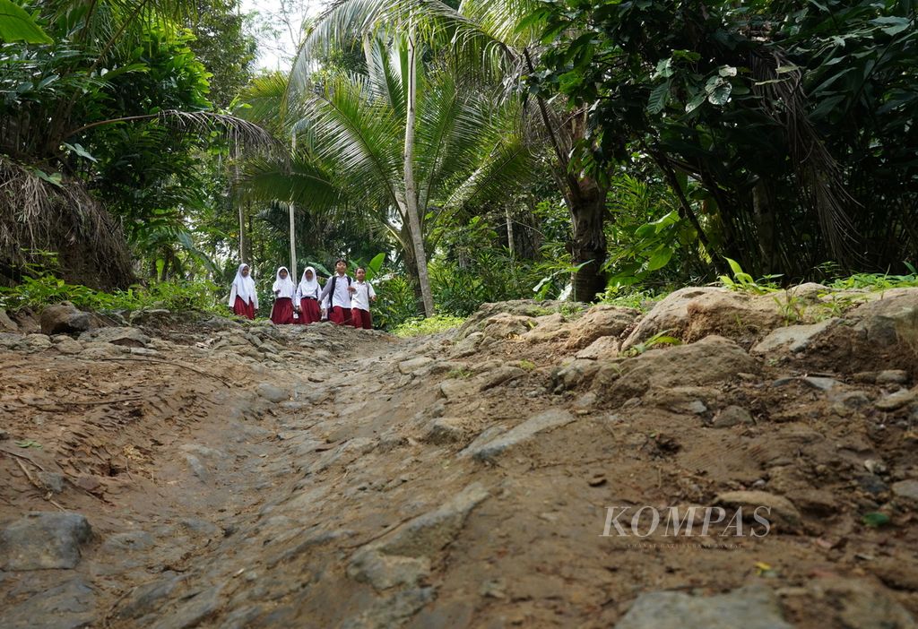 Siswa berjalan kaki melewati jalanan yang rusak akibat tanah bergerak menuju Madrasah Ibtidaiyah Pasawahan, Kecamatan Banjaranyar, Kabupaten Ciamis, Jawa Barat, Selasa (19/7/2022). Mereka butuh 20 menit untuk tiba di sekolah.