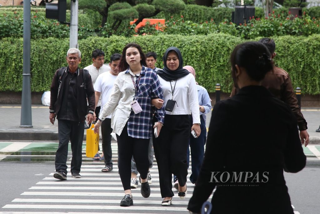 Pekerja kantoran menyeberangi Jalan MH Thamrin, Jakarta, saat jam istirahat siang, Jumat (16/2/2024).