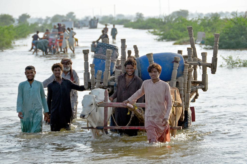 Warga mengungsi bersama barang-barangnya setelah permukiman mereka dilanda banjir menyusul hujan lebat di daerah Sohbatpur di Distrik Jaffarabad, Provinsi Balochistan, Pakistan, Minggu (28/8/2022). 