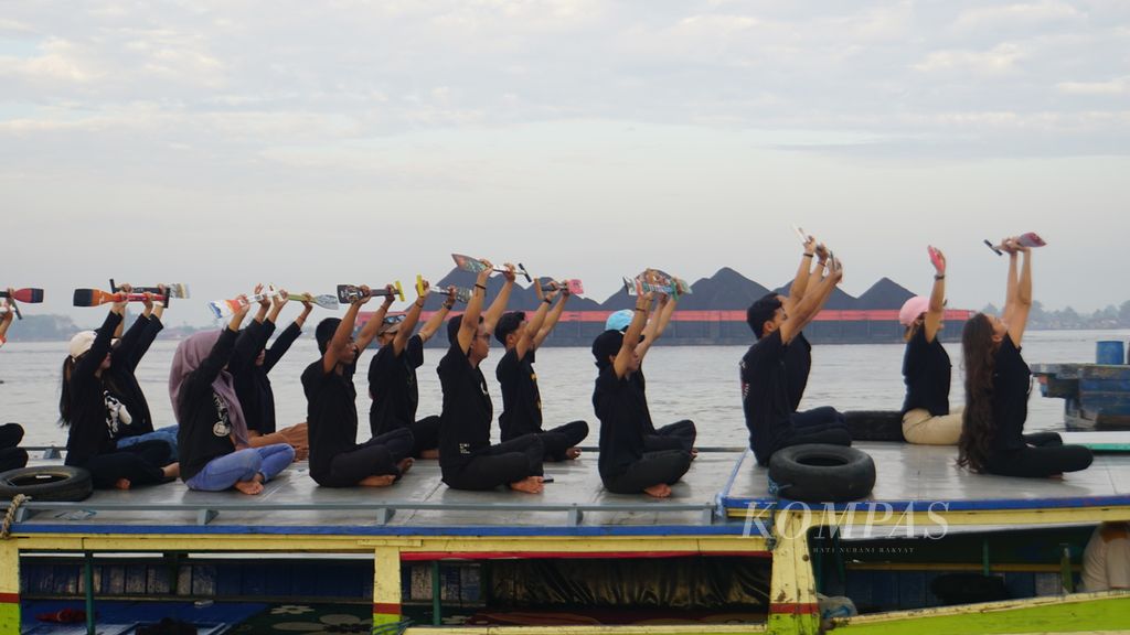 Sejumlah anak muda yang tergabung dalam berbagai komunitas seni melakukan ritus Pangayuh atau ritual mengayuh dayung di Sungai Barito dekat Dermaga Pasar Terapung Muara Kuin, Banjarmasin, Kalimantan Selatan, Sabtu (9/9/2023). 