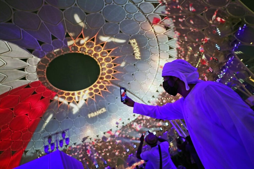 Seorang pria tengah berswafoto di bawah kubah  Al Wasl Plaza yang bermandikan cahaya dengan gambar bendera nasional Perancis di Dubai Expo 2020 yang digelar di Dubai, Uni Emirat Arab, pada Sabtu (2/10/2021).