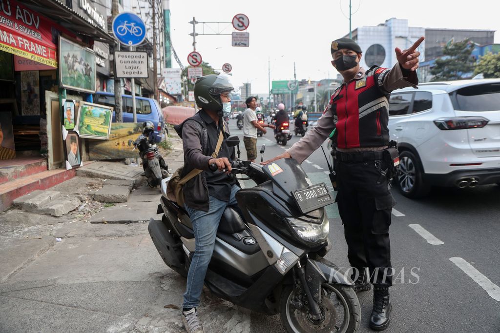 Anggota polisi menegur pengendara sepeda motor yang melawan arus di Jalan Mampang Prapatan, Jakarta Selatan, Senin (4/8/2023). 