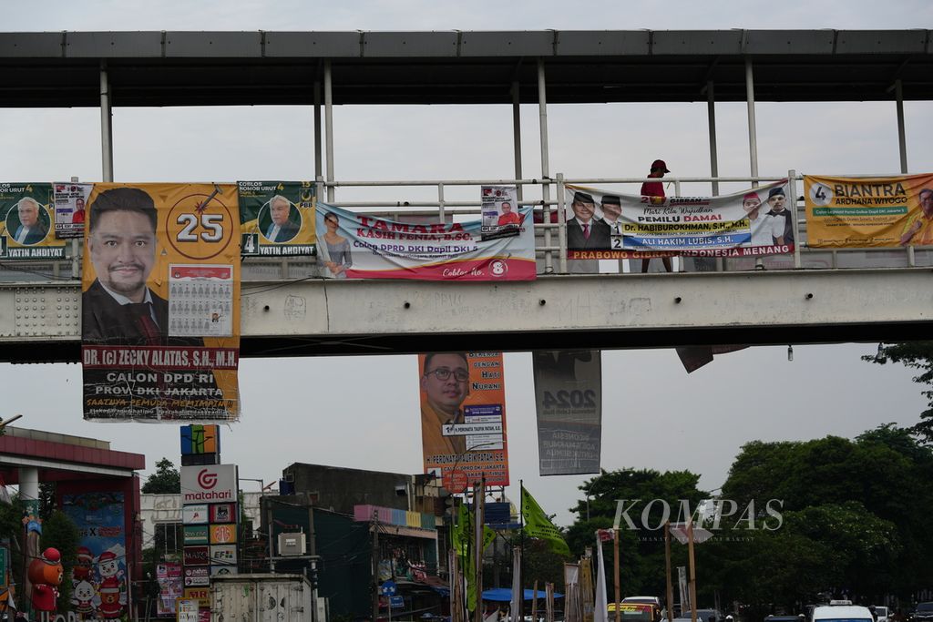 Warga melintasi baliho calon anggota legislatif di jembatan penyeberangan orang Pasar Gembrong, Jakarta Timur, Rabu (3/1/2024). 