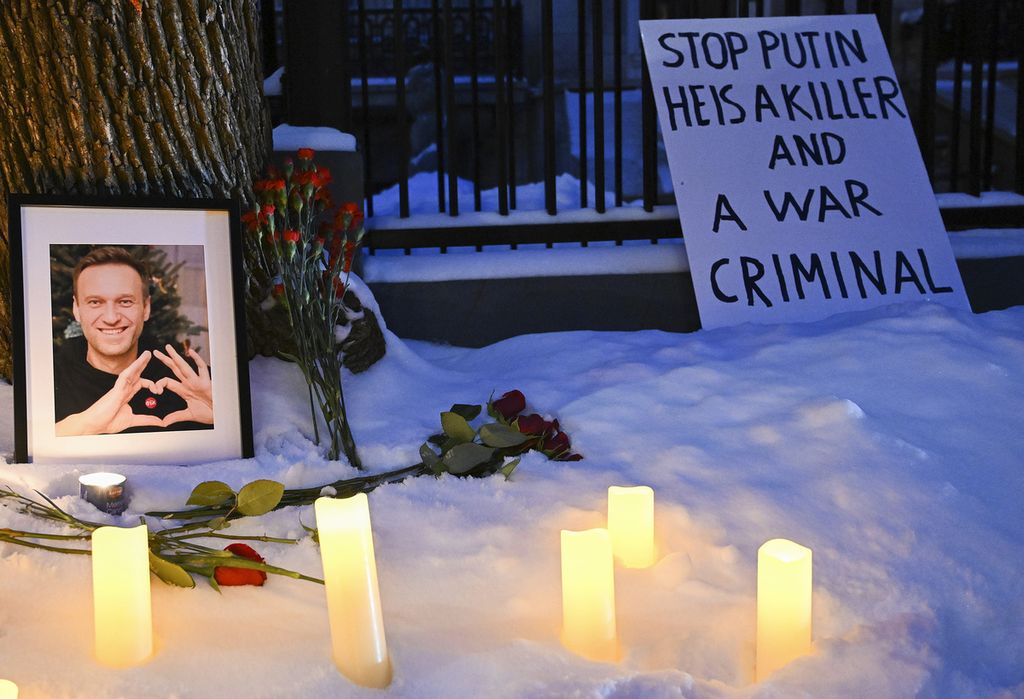 Bunga dan lilin diletakkan di samping foto Alexei Navalny di luar konsulat Rusia di Montreal, Kanada, Jumat (16/2/2024). 