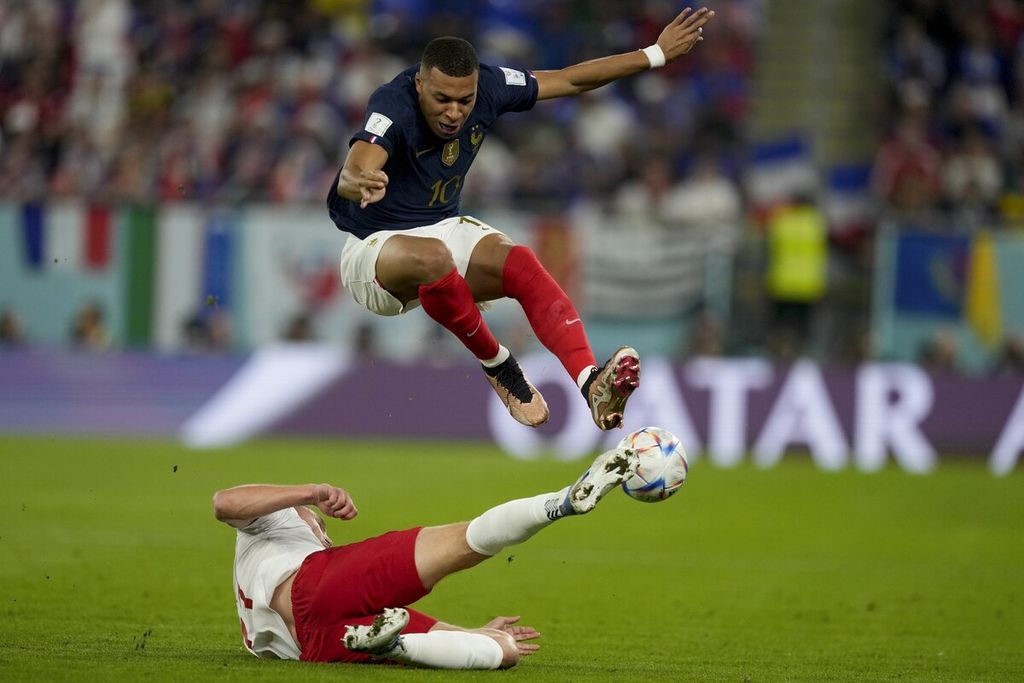 Penyerang Perancis, Kylian Mbappe (atas), menghindari tekel pemain Denmark, Rasmus Kristensen, pada laga penyisihan Grup D Piala Dunia Qatar di Stadion 974 di Doha, Sabtu (26/11/2022) malam. Perancis menang, 2-1. 