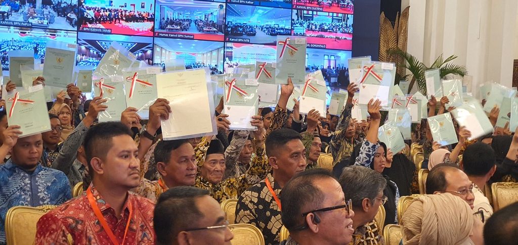 Warga menunjukkan sertifikat yang baru dibagikan. Lebih dari 2,5 juta sertifikat dibagikan dalam acara penyerahan sertifikat tanah dan peluncuran sertifikat tanah elektronik secara daring dan luring di Istana Negara, Jakarta, Senin (4/12/2023).