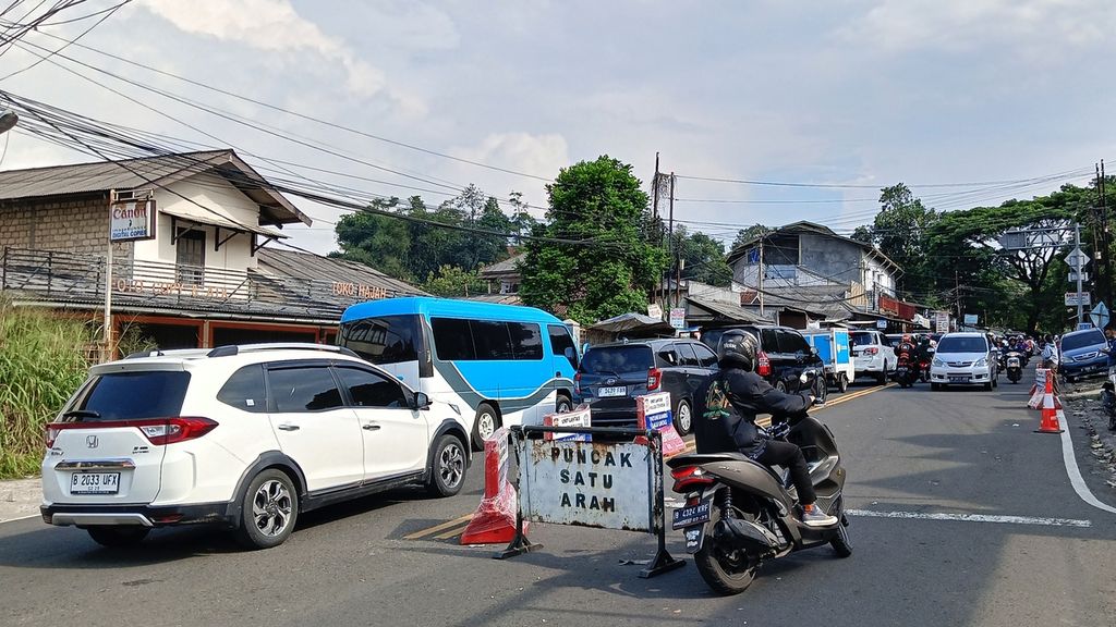 Pengendara motor menyalip mobil yang terjebak kemacetan di Jalan Raya Ciawi, Sabtu (13/4/2024). Di sisi lajur kanan, kendaraan dari arah Jakarta harus menunggu atau ditahan tidak masuk ke jalur Puncak karena polisi memberlakukan sistem satu arah.
