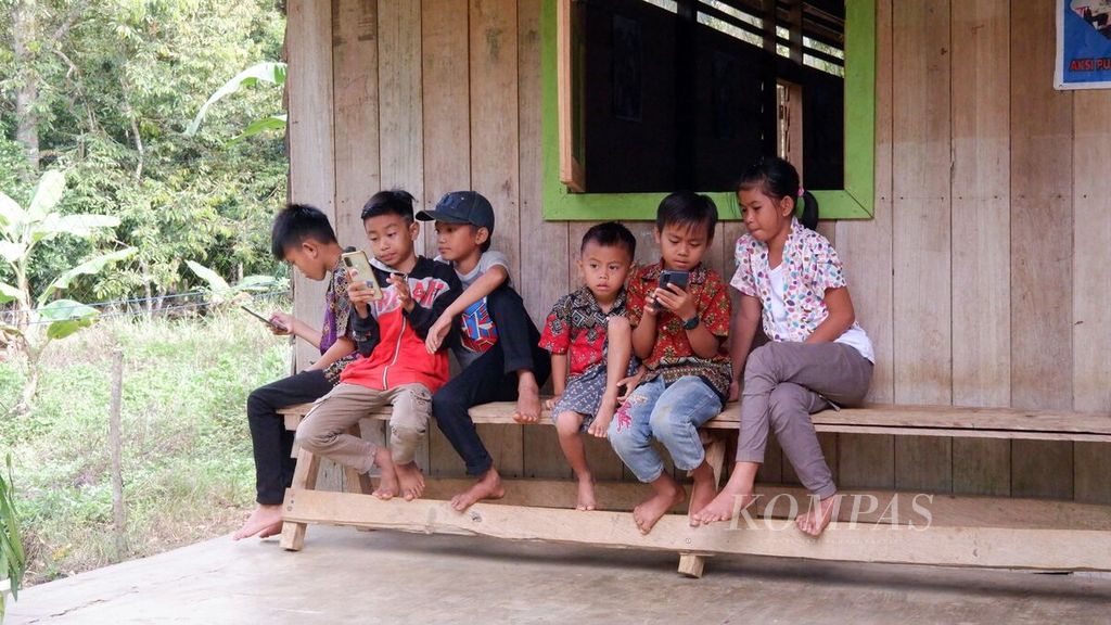 Anak-anak bermain gawai di Dusun Napu, Desa Cantung Kiri Hulu, Kecamatan Hampang, Kabupaten Kotabaru, Kalimantan Selatan, Minggu (13/6/2021). Meskipun tinggal di daerah pedalaman Pegunungan Meratus dengan area tak bersinyal, anak-anak di sana tetap akrab dengan gawai.