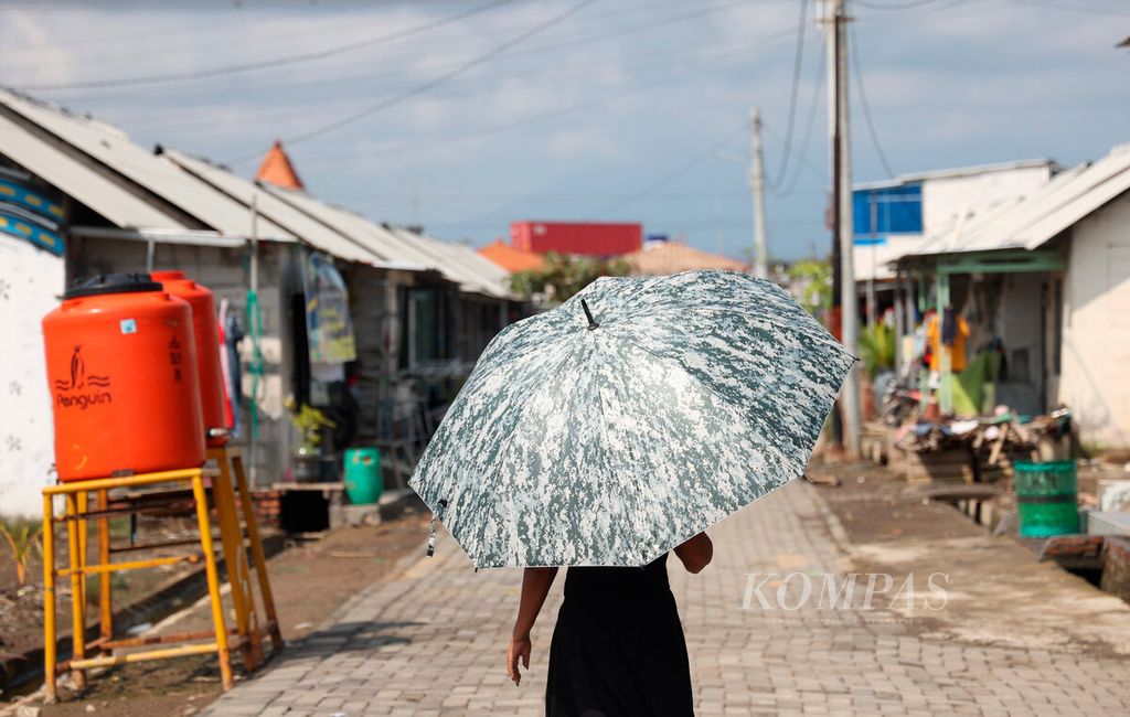 Warga di Kampung Tambakrejo, Kota Semarang, Jawa Tengah, Kamis (4/5/2023), menggunakan payung untuk mengurangi panas yang beberapa pekan ini terjadi.