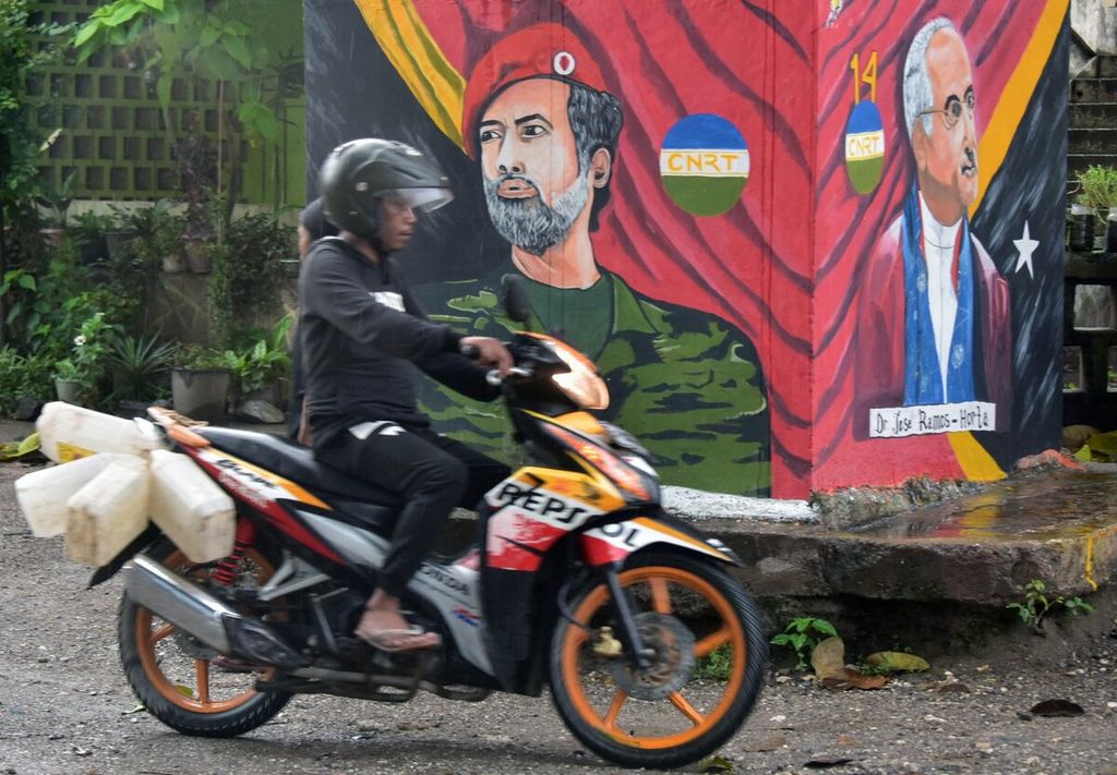 Pengendara sepeda motor melewati mural yang menampilkan sosok pemimpin Timor Leste Xanana Gusmao (kiri) dan Jose Ramos Horta menjelang pemilihan presiden di Dili, Timor Leste, Jumat (18/3/2022). 