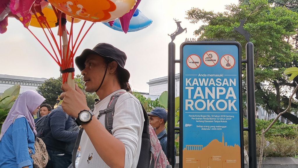 Lalu lalang pedagang dan pengunjung melewati plang bertuliskan kawasan tanpa rokok di salah satu pintu masuk dekat Stasiun Bogor, Alun-alun Kota Bogor, Jawa Barat, Jumat (30/6/2023).