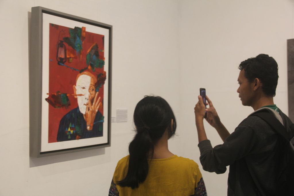 Visitors take pictures of a painting featuring pantomime artist Jemek Supardi in the Mikul Duwur Mendhem Jero #2 exhibition: Pertemuan, on Friday (15/9/2023) at Bentara Budaya Yogyakarta, Kota Yogyakarta. The exhibition, which is participated by 23 artists and runs from 15-21 September 2023, is part of the series of activities to celebrate the 41st anniversary of Bentara Budaya on 26 September 2023.
