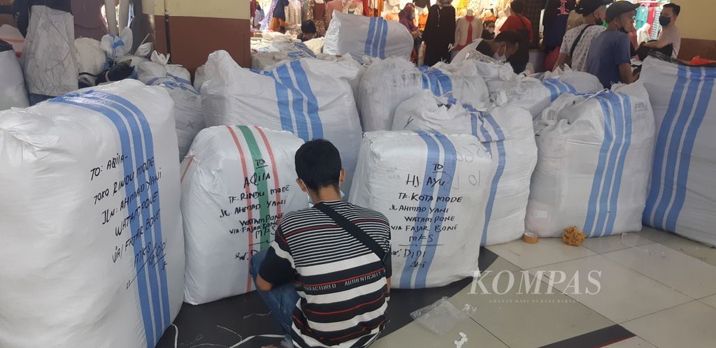 Seseorang duduk di antara karung-karung paket produk pakaian pesanan pelanggan di Pasar Tanah Abang Blok B, Jakarta Pusat, Selasa (29/3/2022).