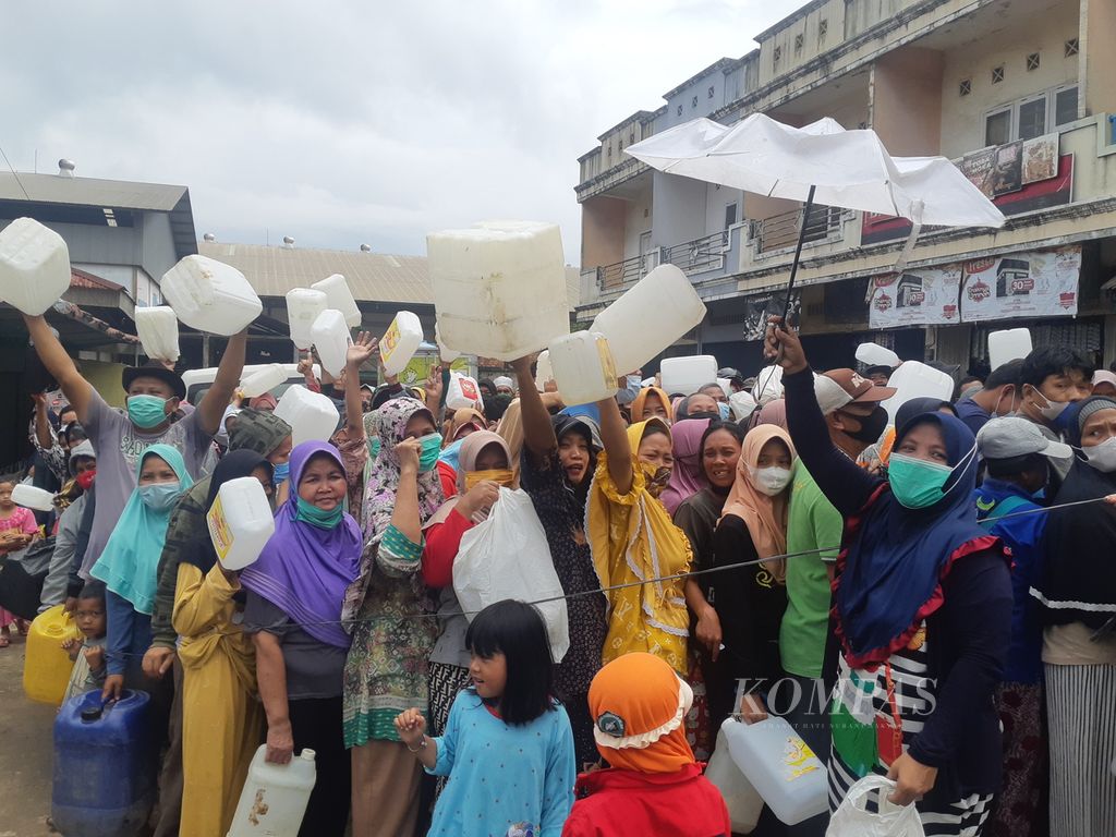 Sejumlah warga mengangkat jerigen minyak sebagai bentuk protes pada kelangkaan minyak goreng saat mengantre operasi pasar di Pasar Alang-Alang Lebar, Palembang, Sumatera Selatan, Sabtu (5/3/2022). Sampai saat ini, distribusi minyak goreng masih bermasalah menyebabkan warga kesulitan mendapatkan minyak goreng.