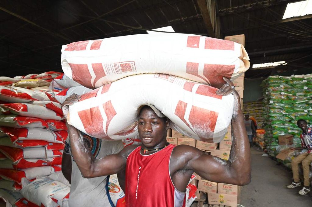 Seorang pekerja tengah mengangkat dua karung tepung gandum dari sebuah gudang di Adjame, di Abidjan pada 11 April 2022.