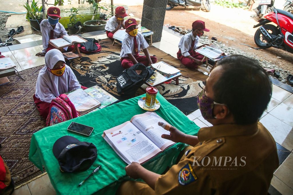 Suhendra (53), guru kelas III SDN Pondok Petir 2, Bojongsari, Depok, Jawa Barat, mengajar anak didiknya secara tatap muka di teras rumah salah seorang wali murid, Senin (31/8/2020).