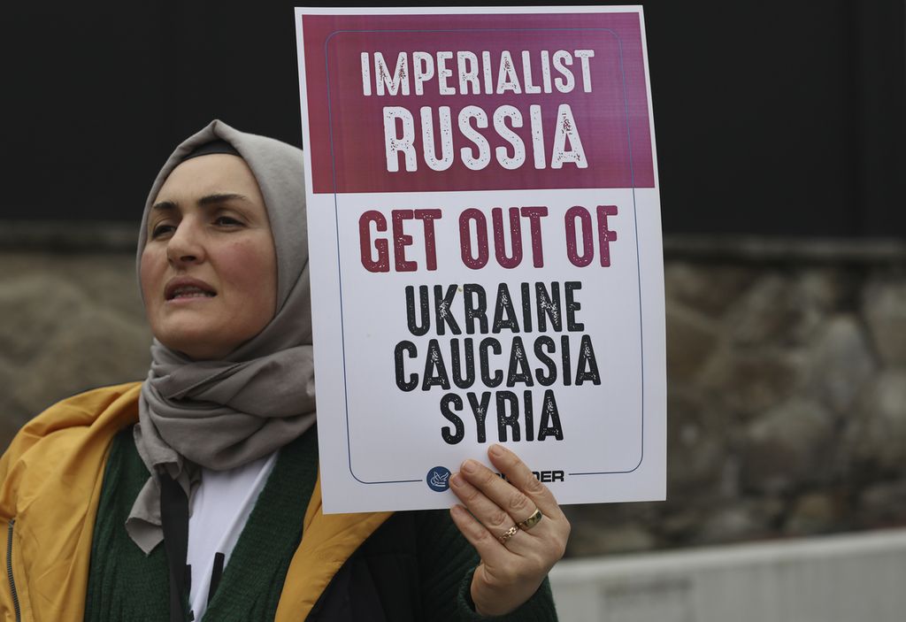 Seorang warga mengangkap plakat berisi penolakan atas serangan Rusia ke Ukraina dalam unjuk rasa yang digelar di depan kantor Kedutaan Besar Rusia di Ankara, Turki pada Sabtu (2/2/2022).