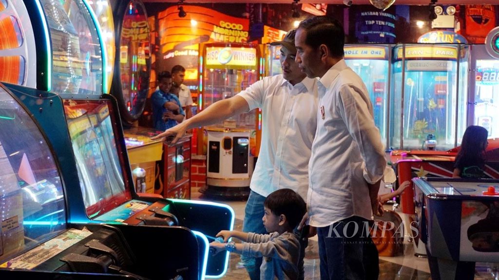 Presiden Joko Widodo (kanan) menemani cucunya, Jan Ethes Sri Narendra, bermain gim di Mal Malioboro, Yogyakarta, Kamis (6/6/2019). Putra kedua Presiden, Kaesang Pangarep, ikut menemani. 