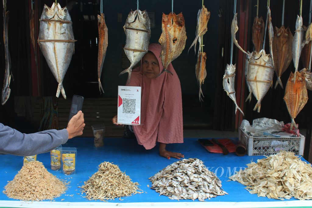 Pembeli melakukan pindai kode batang untuk membayar saat membeli produk UMKM di sentra penjualan ikan asin di Kecamatan Leupung, Kabupaten Aceh Besar, Aceh, 21 Juni 2022. Pelaku usaha warga pesisir di Aceh Besar mulai menerapkan sistem digitalisasi agar memudahkan transaksi dan penjualan.