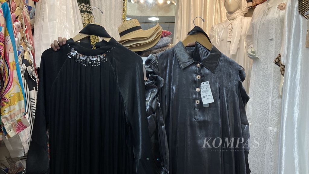 A fashion kiosk employee shows a robe made from Shimmer which is sold at the Thamrin City shopping center, Jakarta, Monday (8/4/2024) afternoon. Premium <i>shimmer</i> robes (left) are more expensive than standard <i>shimmer</i> robes (right). The difference in the quality of the <i>shimmer</i> material lies, among other things, in the flexibility and smoothness of the material as well as the level of shine of the material. Shimmer refers to a type of fabric that has a sparkling effect when exposed to light. Clothing made from <i>shimmer</i> became a trend after going viral on social media.