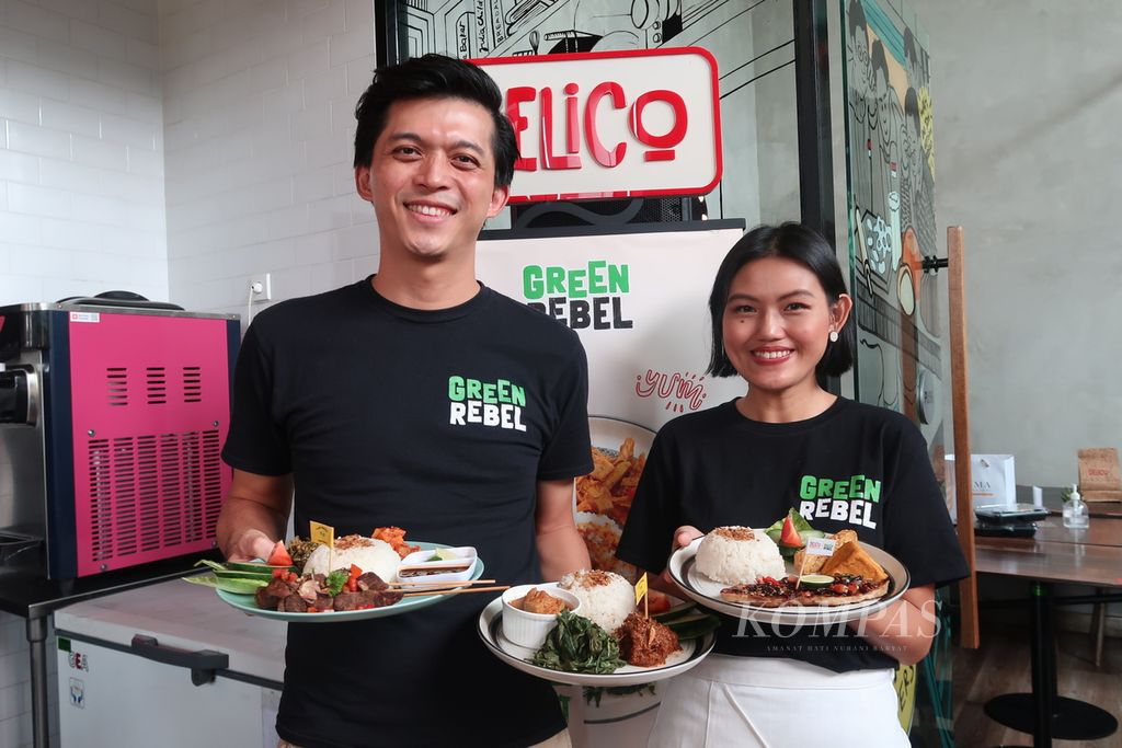 Kedua pendiri Green Rebel, Max Mandias dan Helga Angelina, berpose bersama menu makanan di Delico Café yang menggunakan daging dari produk nabati buatan mereka di Jakarta, Jumat (26/1/2024).