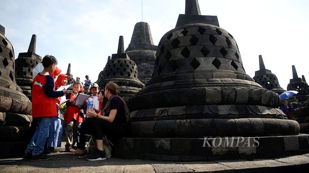 Murid Madrasah Ibtidaiyah Negeri 1 Jombang berlatih berbicara menggunakan bahasa Inggris dengan wisatawan asing di obyek wisata Candi Borobudur, Magelang, Jawa Tengah, Minggu (16/9/2018). Mereka melatih kemampuan berkomunikasi menggunakan bahasa asing.