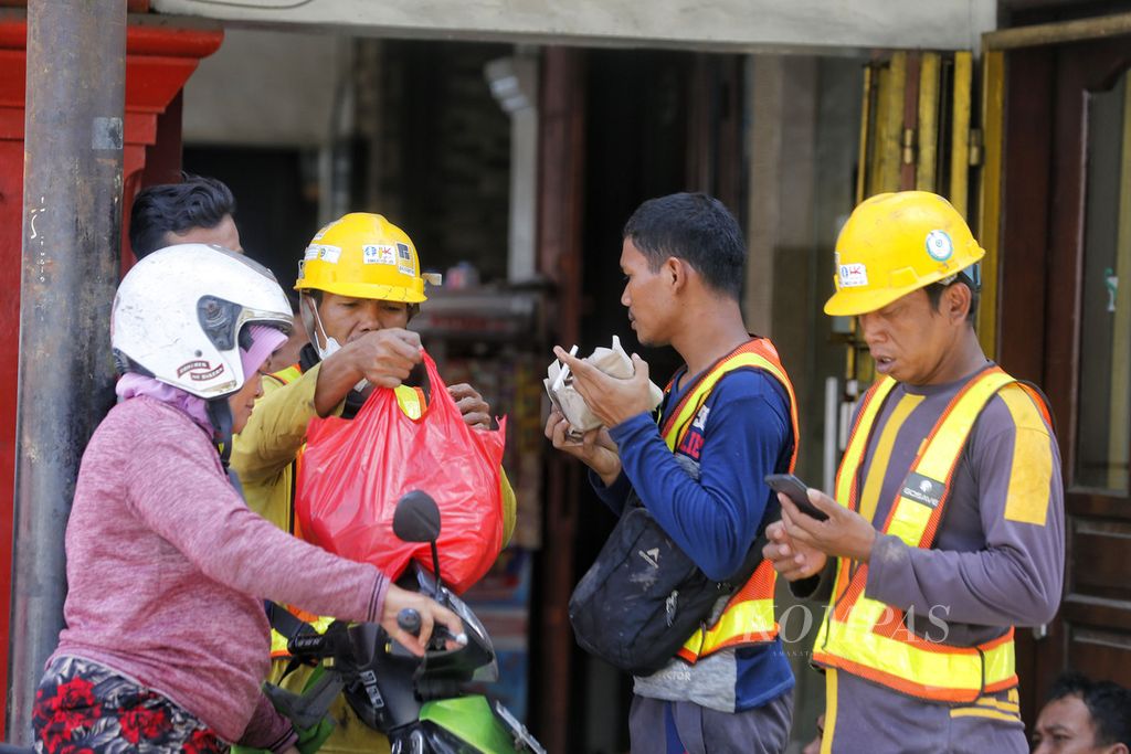 Pekerja pembangunan jalur MRT sedang memesan makanan saat isitrahat siang di kawasan Glodok, Jakarta, Minggu (20/11/2022). Pemerintah mengubah formula penghitungan upah minimum tahun 2023 melalui Peraturan Menteri Ketenagakerjaan No 18/2022 tentang Penetapan Upah Minimum Tahun 2023. 