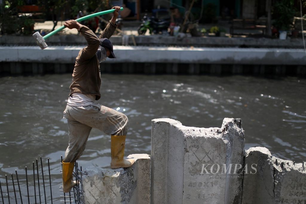 Pekerja meratakan turap beton yang dipasang di bantaran Kali Ciliwung di kawasan Kelurahan Ancol. Pademangan, Jakarta Utara, Selasa (19/11/2019). 
