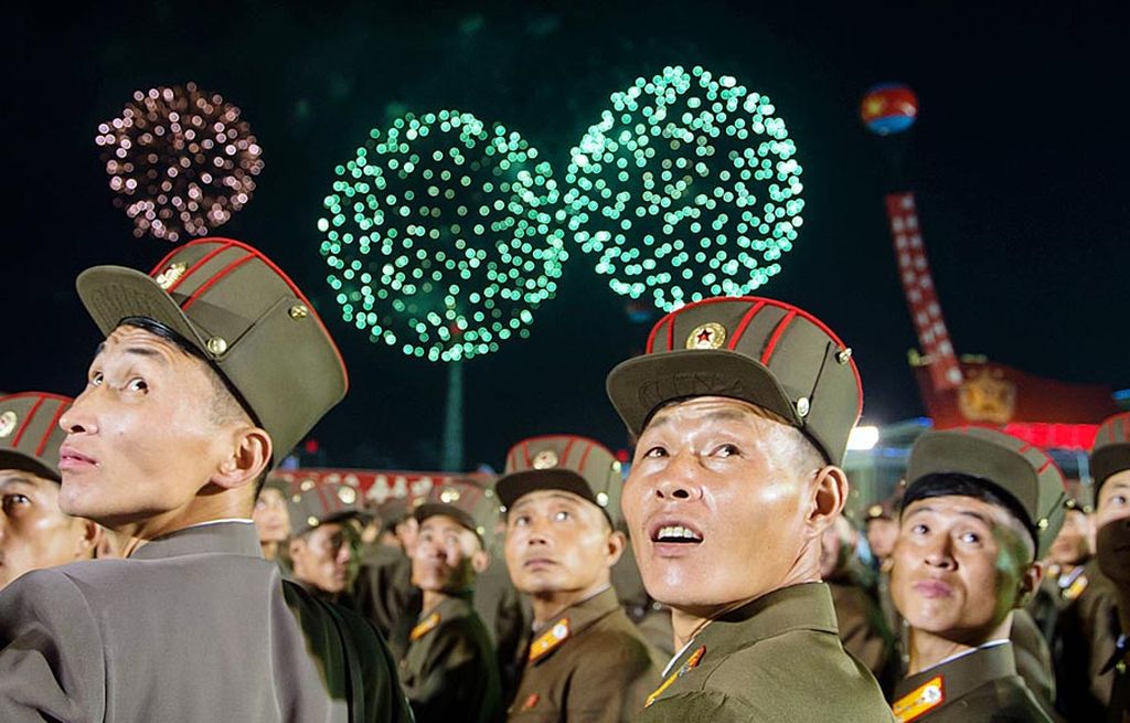 Anggota Tentara Rakyat Korea (KPA) menyaksikan pesta kembang api dalam perayaan massal di Pyongyang, Korut, Rabu (6/9),  untuk menghormati para ilmuwan yang berhasil melakukan uji coba nuklir terbesar Korut, akhir pekan lalu. Warga Pyongyang berbaris di tepi jalan saat bus yang membawa para ilmuwan lewat dan melemparkan confetti saat para ilmuwan tiba di lapangan Kim Il Sung, Pyongyang.