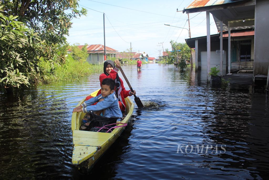 Warga Kelurahan Palangka, Kota Palangkaraya, Kalimantan Tengah, menggunakan jukung atau sampan kayu untuk beraktivitas di tengah banjir pada Jumat (10/2/2023). 