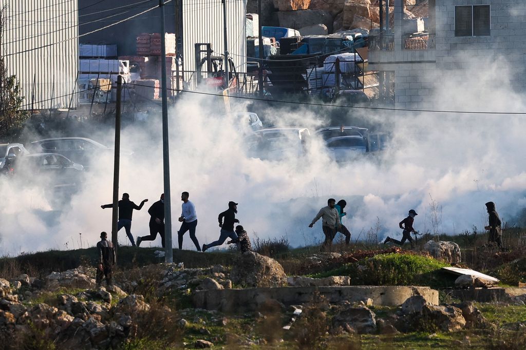 Warga Palestina melempari militer Israel dengan batu di tengah kepungan gas air mata saat bentrokan di Ramallah, Kamis (26/1/2023) (AFP/AHMAD GHARABLI)