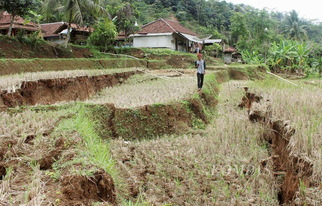 Warga melintasi sawah yang ambles akibat gerakan tanah di Desa Waringinsari, Kecamatan Takokak, Kabupaten Cianjur, Jawa Barat, Selasa (3/10). Selain merusak 32 hektar sawah, bencana tersebut juga membuat 380 rumah rusak dan 420 rumah lainnya terancam rusak.