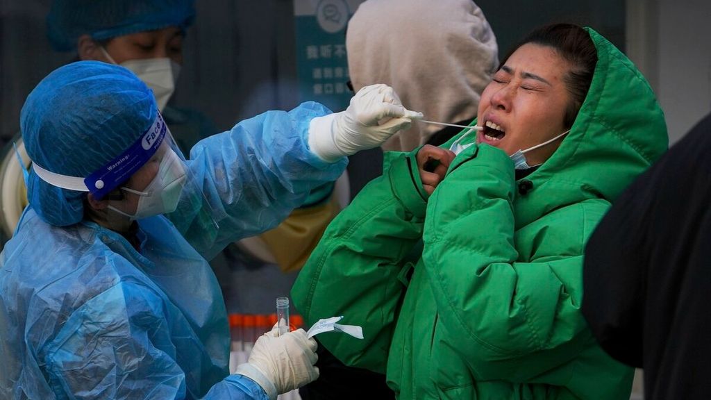 A health worker administers a Covid-19 test, a travel requirement, on Sunday (12/26/2021) at a Covid-19 testing facility in Beijing, China. Chinese airlines have canceled numerous flights under Beijing’s strict zero-Covid restrictions. 